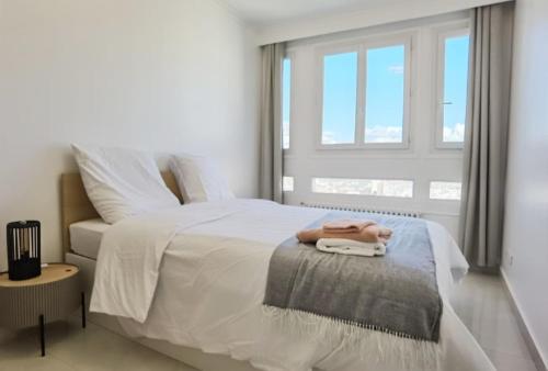 ein Schlafzimmer mit einem weißen Bett mit einem Fenster in der Unterkunft Modern 2-Bed Apt 80m2 with Elevator FREE Parking N19-25 in Paris