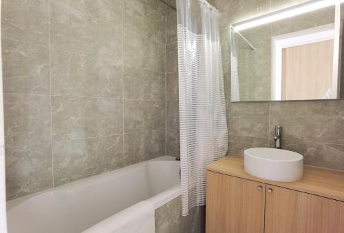 ein Badezimmer mit Waschbecken, Badewanne und Spiegel in der Unterkunft Modern 2-Bed Apt 80m2 with Elevator FREE Parking N19-25 in Paris