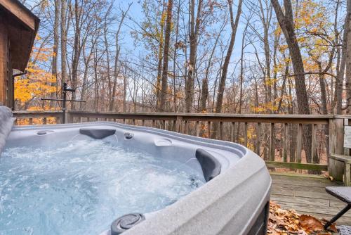 a jacuzzi tub on a deck next to a fence at Huge Cabin w Hot Tub, Deck, Grill, Fire Pit, WiFi in Berkeley Springs