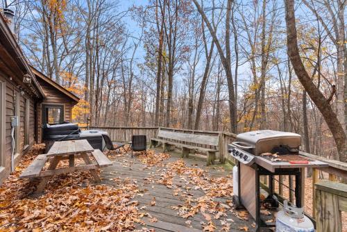 a backyard with a grill and a picnic table and benches at Huge Cabin w Hot Tub, Deck, Grill, Fire Pit, WiFi in Berkeley Springs