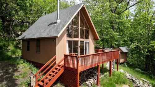 a small house with a large deck in the woods at Rustic-Modern Chalet w/ Fire Pit, Deck & Views in Slanesville, WV in Slanesville