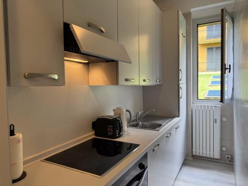a kitchen with white cabinets and a sink and a window at Vener Appartament - A due passi dal Lago in Ossuccio