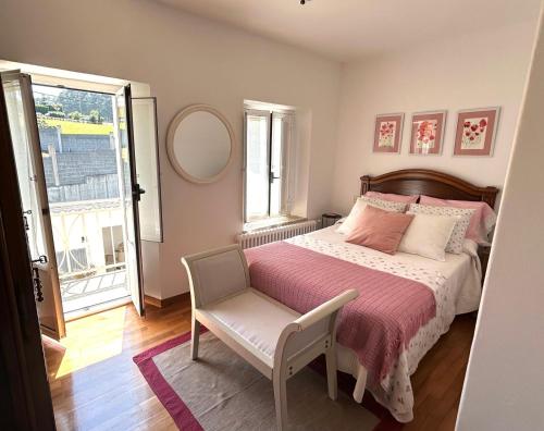 a bedroom with a bed and a chair and a window at Casa Pancha in Ribadeo