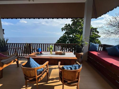 a porch with a table and chairs and the ocean at Kampung Kecil Beach Front Boutique Hotel in Kubu