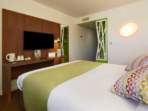 a hotel room with a large bed and a flat screen tv at Campanile Ales Centre - Cévennes in Alès