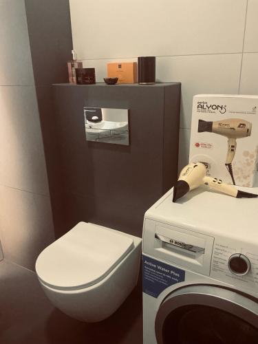 a small bathroom with a toilet and a machine at Apartament 30 City Park nad jeziorem in Szczecinek