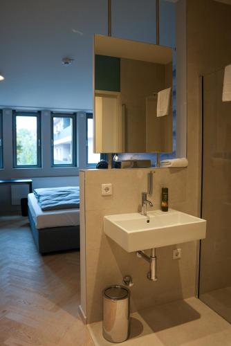 Un baño con lavabo y cama. en qnorke Hotel, en Berlín
