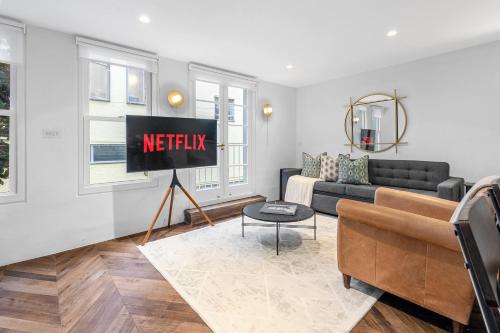 a living room with a couch and a tv at Contemporary 2-Bedroom Escape in Notting Hill in London