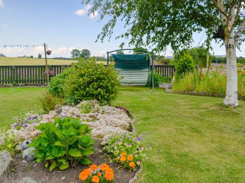 a garden with flowers in a yard with a fence at Laurel Bank in Alyth