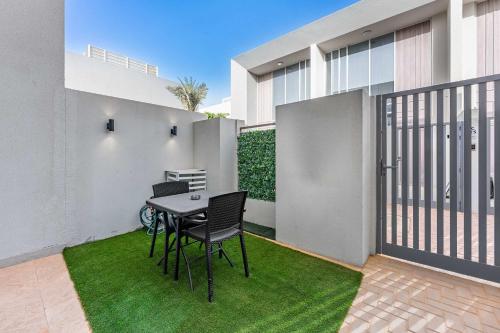 un patio avec une table et des chaises sur l'herbe dans l'établissement StayShort - Cozy 1BR Townhouse loft style located in Rukan Community, à Nadd Shubayḩ