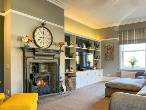 a living room with a fireplace and a clock on the wall at Cracken Cottage - Uk48297 in Chinley
