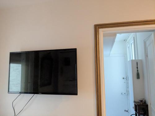 a flat screen tv hanging on a wall next to a mirror at Cosy renovated little nest in historic MONTMARTRE in Paris