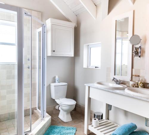 een badkamer met een toilet, 2 wastafels en een douche bij SableChateau Beachfront Guesthouse in Stompneusbaai