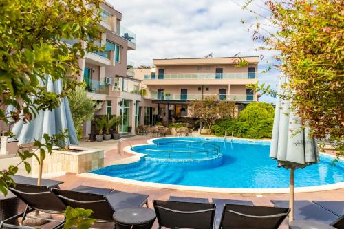 a swimming pool with chairs and umbrellas in front of a building at Selena Beach Family Hotel - All Inclusive Light in Sozopol