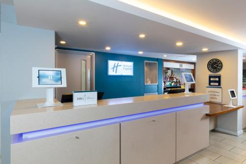 a lobby with a counter with a tv on it at Holiday Inn Express Birmingham Oldbury by IHG in Oldbury