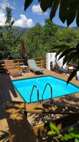 a swimming pool with two chairs and a table at Kedra Village Retreats - Mountain Escape in Mastoréïka