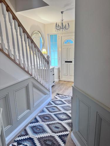 a hallway with stairs and a blue and white rug at Clones Town House in Cluain Eois