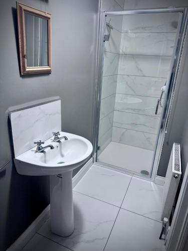 a white bathroom with a sink and a shower at Clones Town House in Cluain Eois