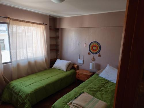two beds in a room with green sheets at A pasos de la playa in Algarrobo