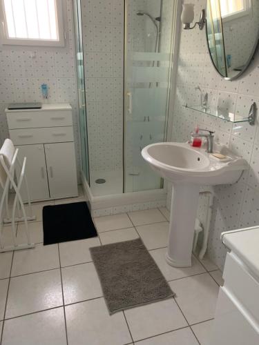 a white bathroom with a sink and a shower at Maison de vacances à Saint Quay Portrieux in Saint-Quay-Portrieux
