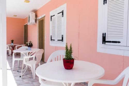Una habitación con dos mesas y sillas blancas y una planta en maceta. en Roussa's Apartments, en Laganas