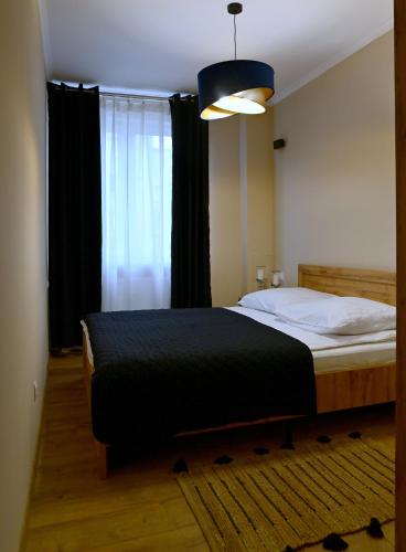a bedroom with a bed with a black blanket at Apartamenty Milano in Tarnobrzeg