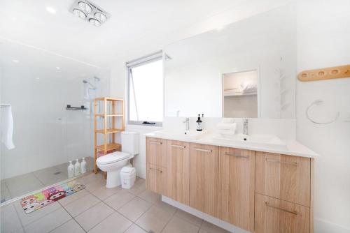 ein Badezimmer mit Waschbecken, Toilette und Spiegel in der Unterkunft Spacious Retreat with Balcony Patio and Family Comfort in Doolandella