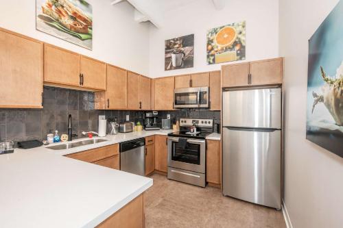 a kitchen with wooden cabinets and a stainless steel refrigerator at The 333 Suites 203 - Stay for 6 in Cincinnati