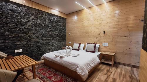 una habitación con una cama y una pared de ladrillo en The clifftonn stays, en Jibhi