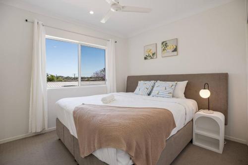 ein weißes Schlafzimmer mit einem großen Bett und einem Fenster in der Unterkunft Affordable Cosy Retreat with Balcony, AC, and Parking in Springwood