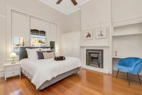 a white bedroom with a bed and a blue chair at Retreat on Chaffey in Mildura