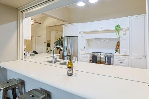 a kitchen with white cabinets and a bottle of wine on a counter at Retreat on Chaffey in Mildura