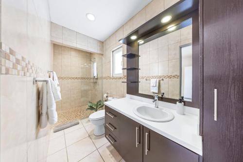 ein Badezimmer mit Waschbecken, Toilette und Spiegel in der Unterkunft Coastal Paradise in Tanki Lender