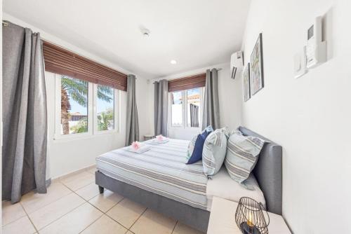 ein Schlafzimmer mit einem Bett und zwei Fenstern in der Unterkunft Coastal Paradise in Tanki Lender