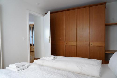 a bedroom with two white beds and wooden cabinets at Fee-Rien in Saas-Fee