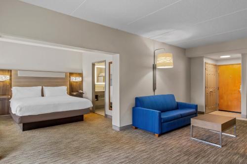 een hotelkamer met een bed en een blauwe stoel bij Holiday Inn Express & Suites Jacksonville South East - Medical Center Area by IHG in Jacksonville