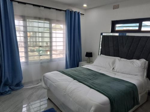 een slaapkamer met een groot bed met blauwe gordijnen bij T & M Apartments in Ndola