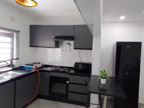 een keuken met zwarte kasten, een wastafel en een fornuis bij T & M Apartments in Ndola