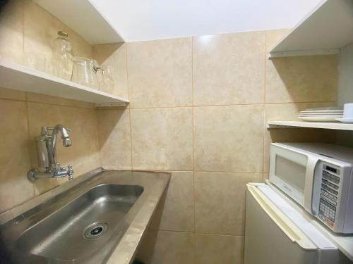 a small kitchen with a sink and a microwave at kitnet no centro histórico in São João del Rei