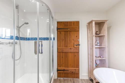 een badkamer met een douche en een houten deur bij 3 Links Court in Brancaster
