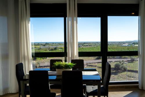 een eetkamer met een tafel, stoelen en ramen bij Apartamento familiar en Torreblanca con vistas al mar, aire acondicionado y cerca de la playa in Torreblanca