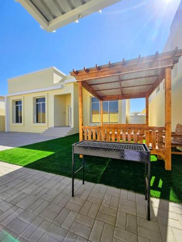 a bench under a wooden pergola in a yard at White Mountain House in Sharīyah