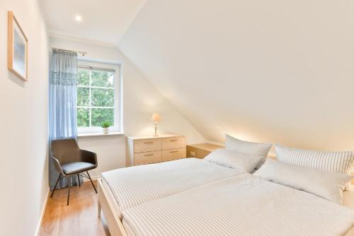 a bedroom with two beds and a chair and a window at Ferienhaus Hygge - nordisches Flair in Toplage in Wiek auf Rügen