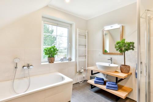 a bathroom with a tub and a sink and a mirror at Ferienhaus Hygge - nordisches Flair in Toplage in Wiek auf Rügen
