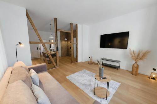 a living room with a couch and a tv on a wall at MILPAU Herne1 - Zentrales, modernes Design-Apartment - Smart TV, Nespresso für 4 Personen in Herne
