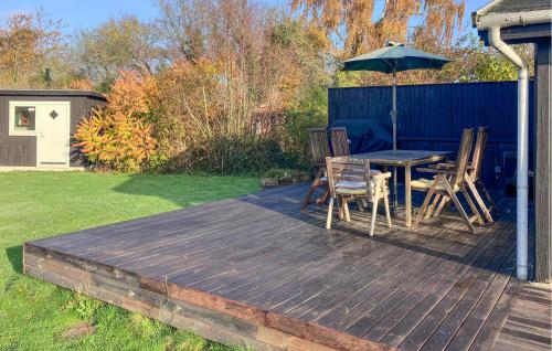 Una terraza de madera con una mesa y una sombrilla. en 2 Bedroom Nice Home In Kirke Såby, en Kirke Såby