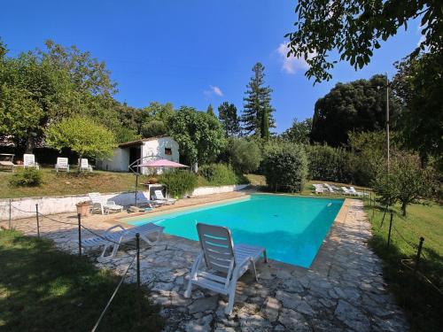 una piscina con dos sillas y una casa en Raffinée Farmhouse with pool views, en Umbertide
