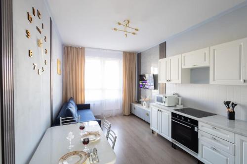 2х комнатные и Однокомнатные квартиры на Туране في Taldykolʼ: مطبخ مع دواليب بيضاء وطاولة مع كراسي