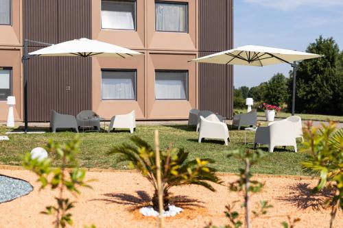 a patio with chairs and umbrellas in front of a building at Hotel Ayri in Medesano