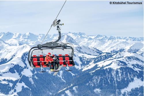 a group of people riding a ski lift over snow covered mountains at Löw Chalet Suite 3 in the heart of Kitzbühel by 360 Estates in Kitzbühel